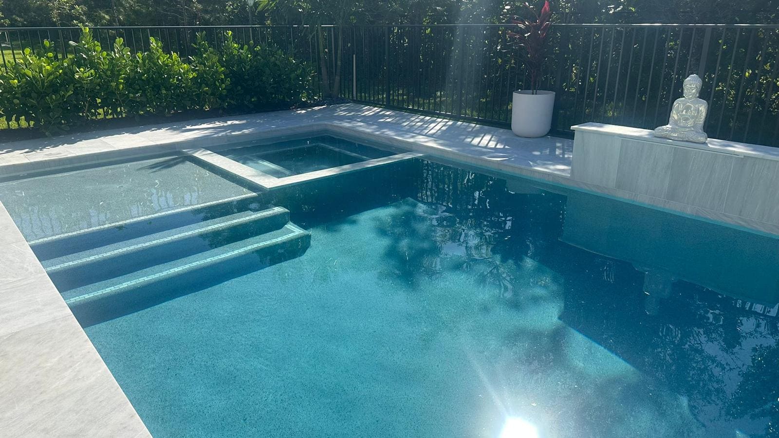 A new pool with steps leading into a shallow area, next to a raised jacuzzi.