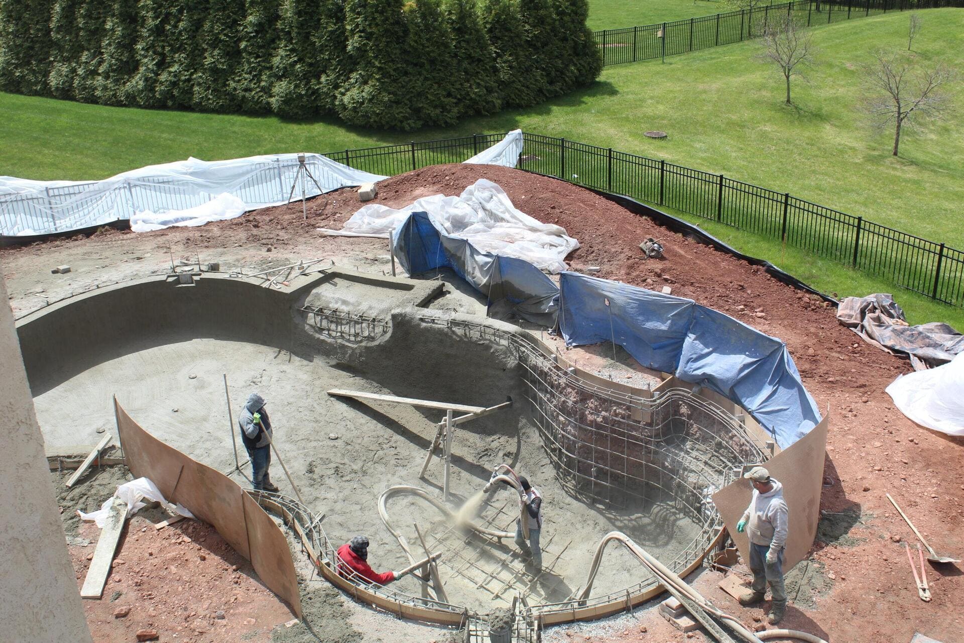 Construction workers applying plaster to the interior of a newly built swimming pool.