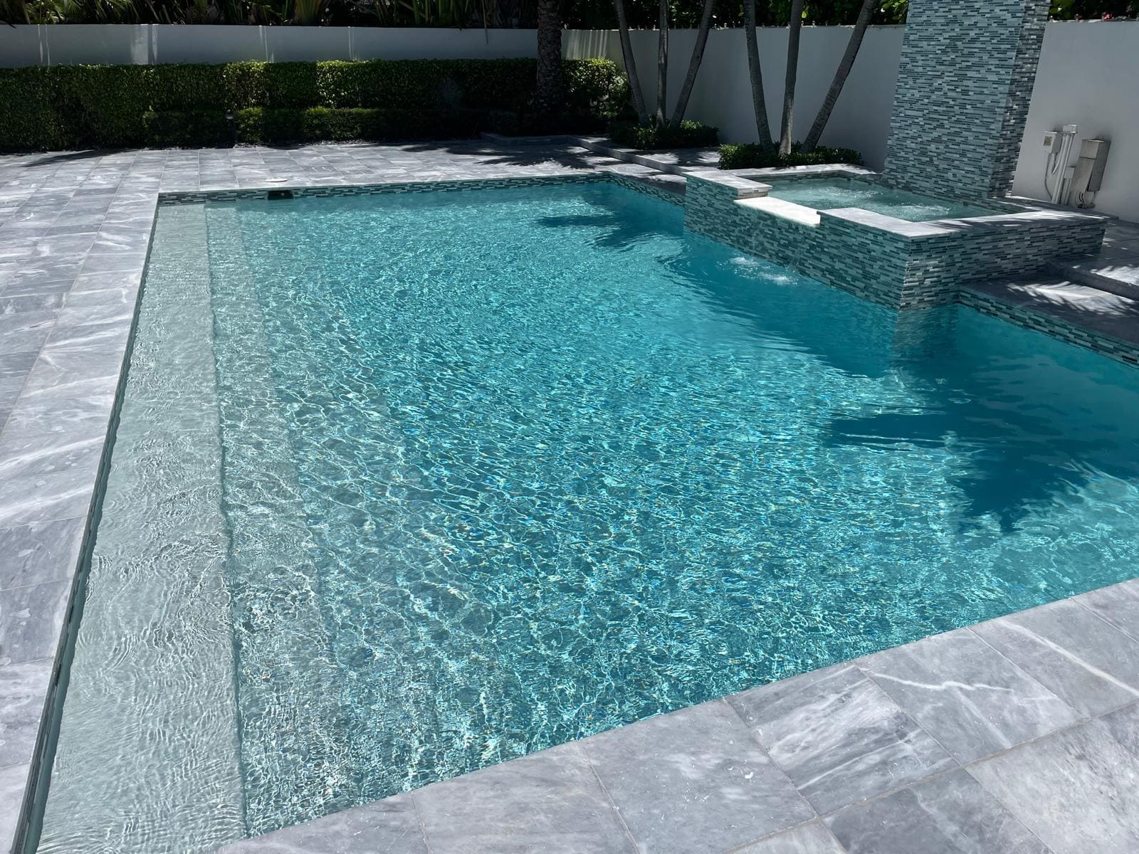 A new pool with steps leading into a shallow area, next to a raised jacuzzi.