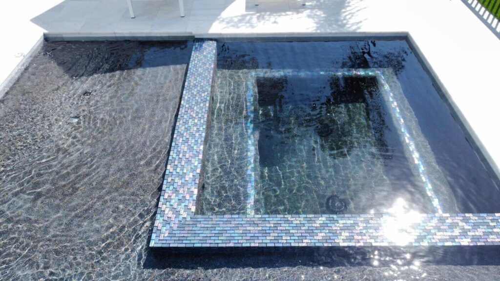 Ultimate Guide to the Most Indestructible Pool Tiles for Lasting Luxury 1 A close-up of a pool's spa area with shimmering iridescent blue tiles and rippling clear water.