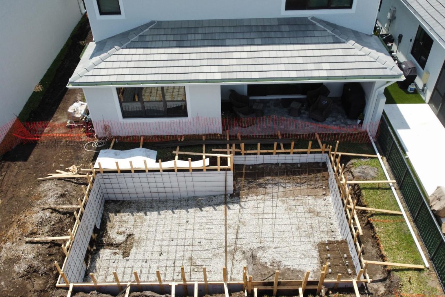 Aerial overhead view of a Florida backyard pool under construction, showing excavation, steel rebar framing, and preparation for concrete installation, illustrating the pool construction timeline in Florida.